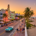 Atardecer en Ocean Drive Miami con luces de neón y autos clásicos.